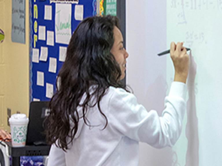 Student writing equations on a white board