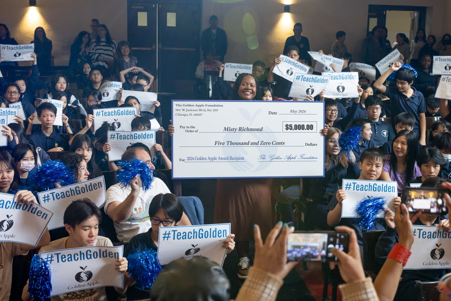 Misty Richmond holds a check from the Golden Apple Foundation