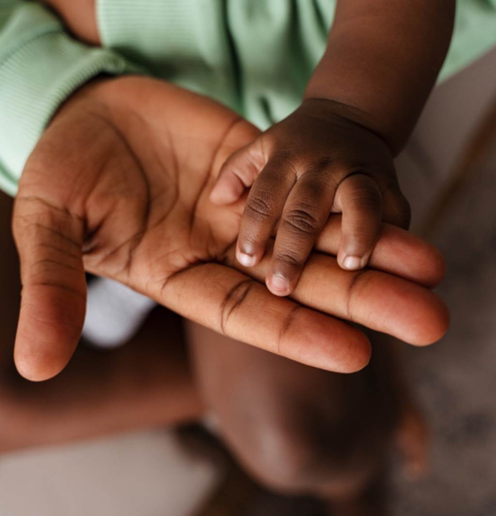 A young child's hand placed over an adults hand.
