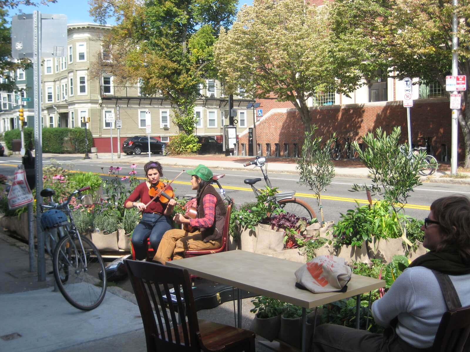 image of 2 people playing music between flowers at a street-side