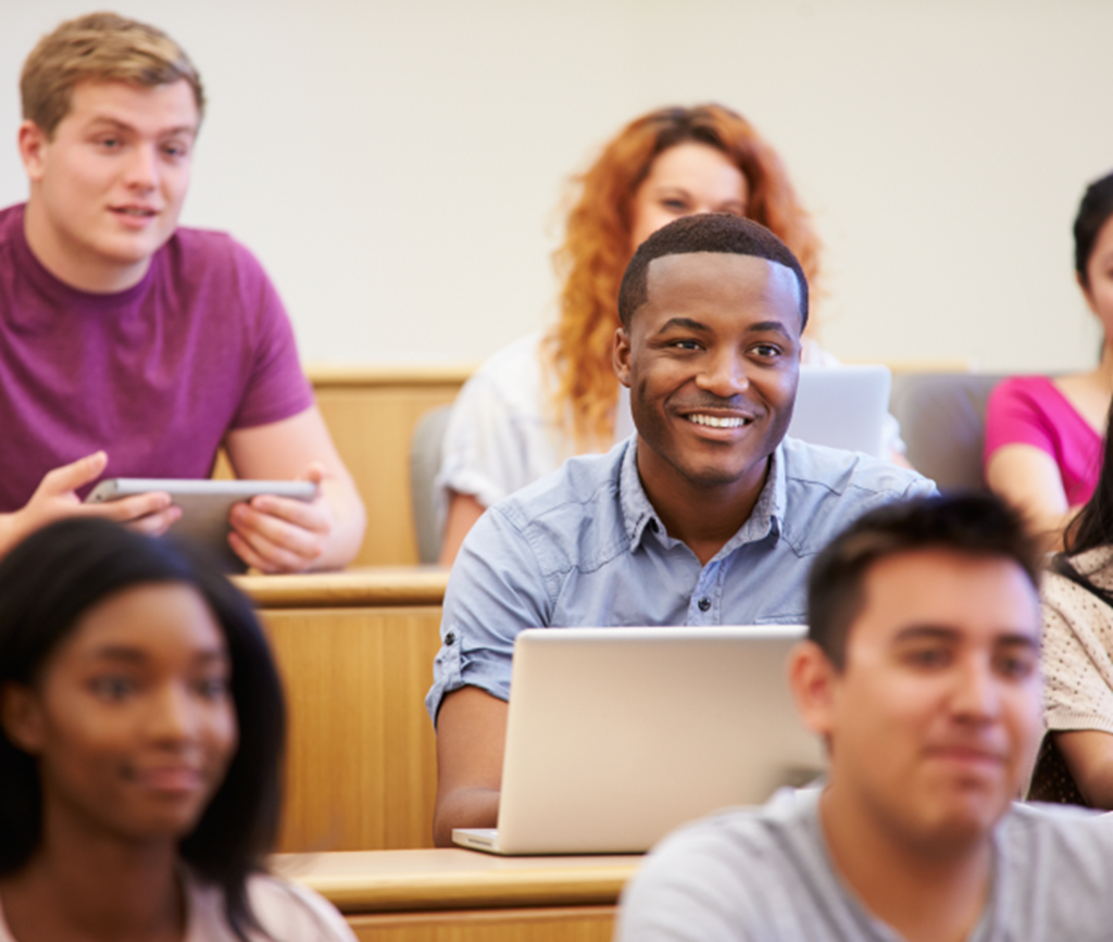 Young man surrounded by students in a college classroom setting