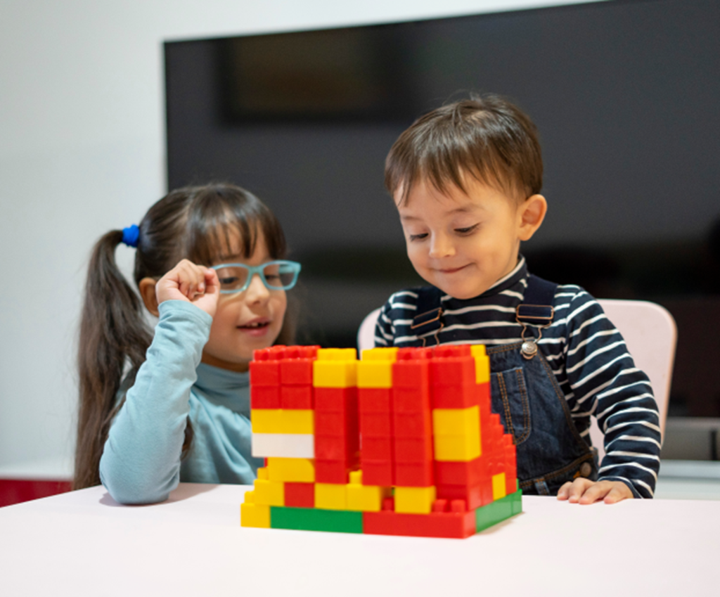 2-year-old and 4-year-old play with lego blocks at home