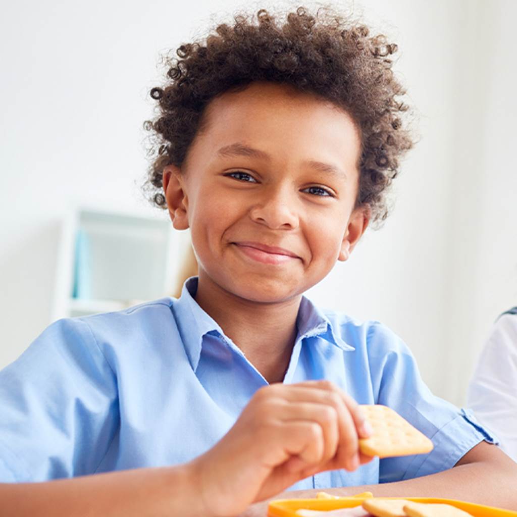 image of smiling student holding cracker