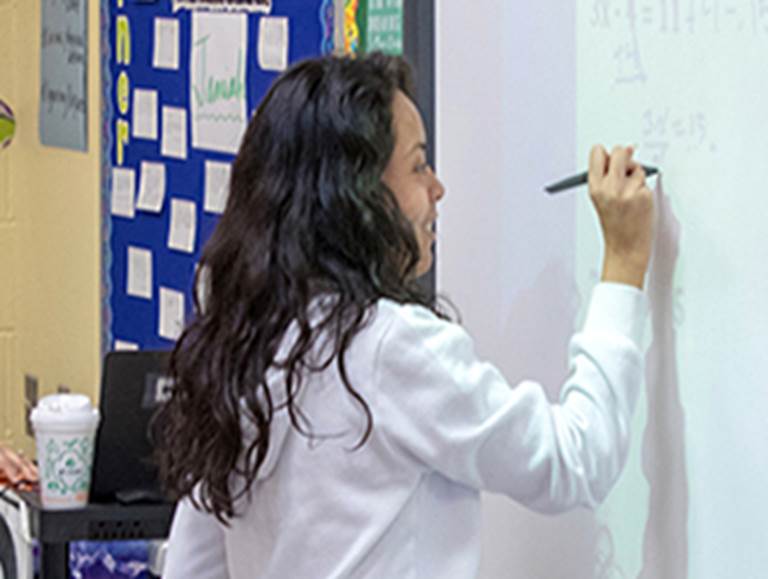 Student writing equations on a white board