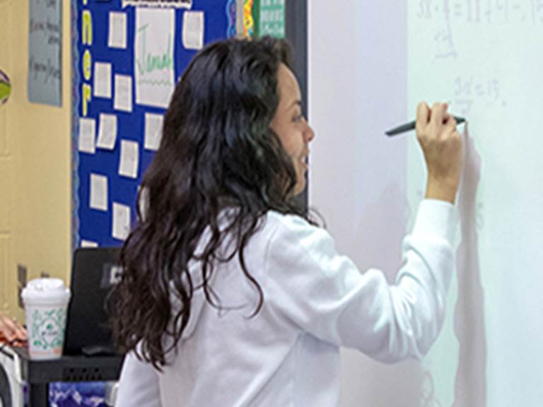 Student writing equations on a white board
