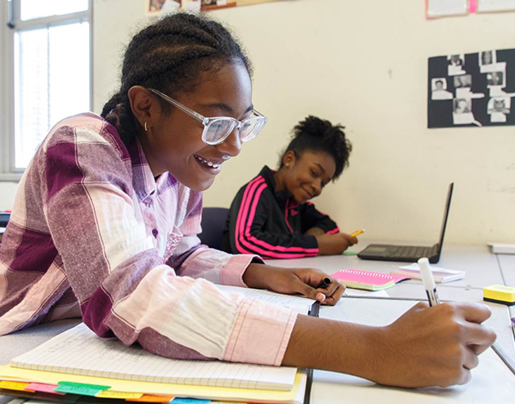 Two smiling students working on classwork