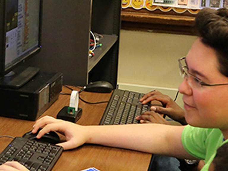 Student using a mouse and keyboard to work on a computer