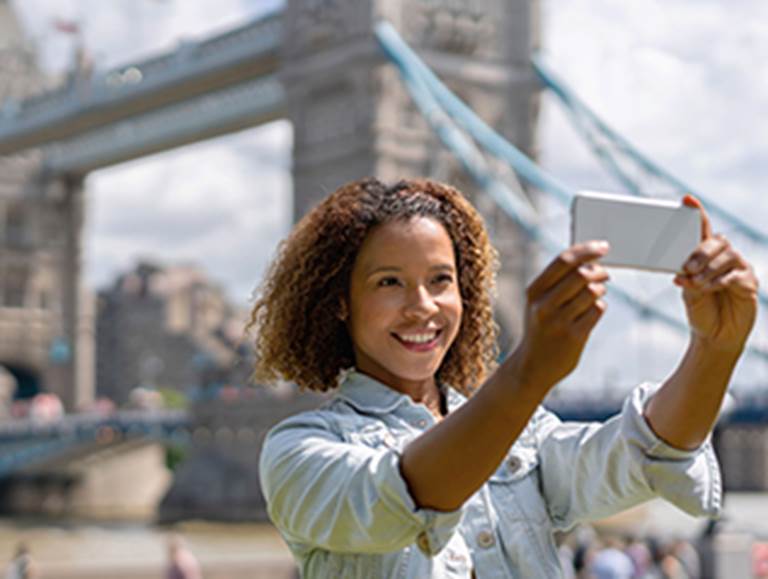 Student taking a selfie with a bridge in the background