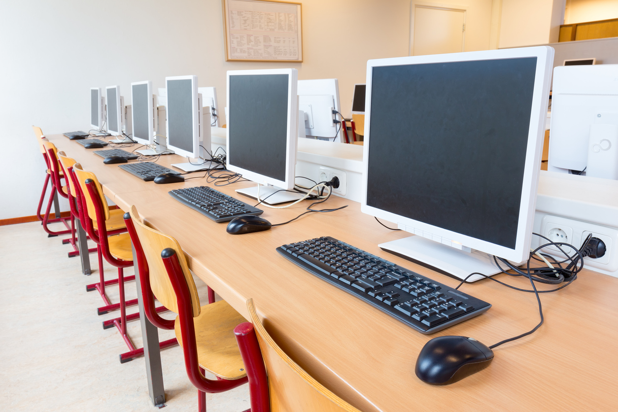 Row of computer screens with mouse and keyboards sitting on a table