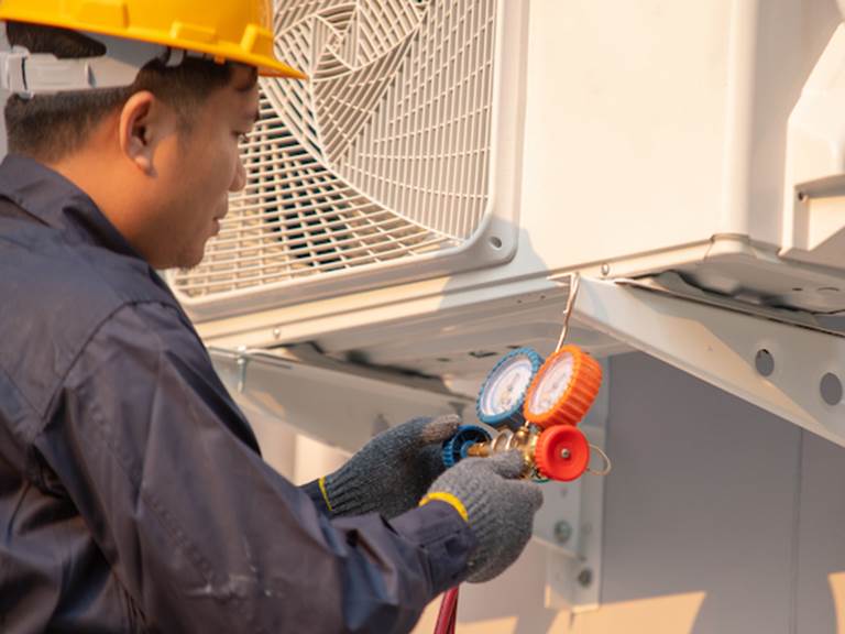 A technician adjusts an air conditioner