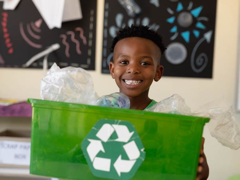 smiling student holding recycling can