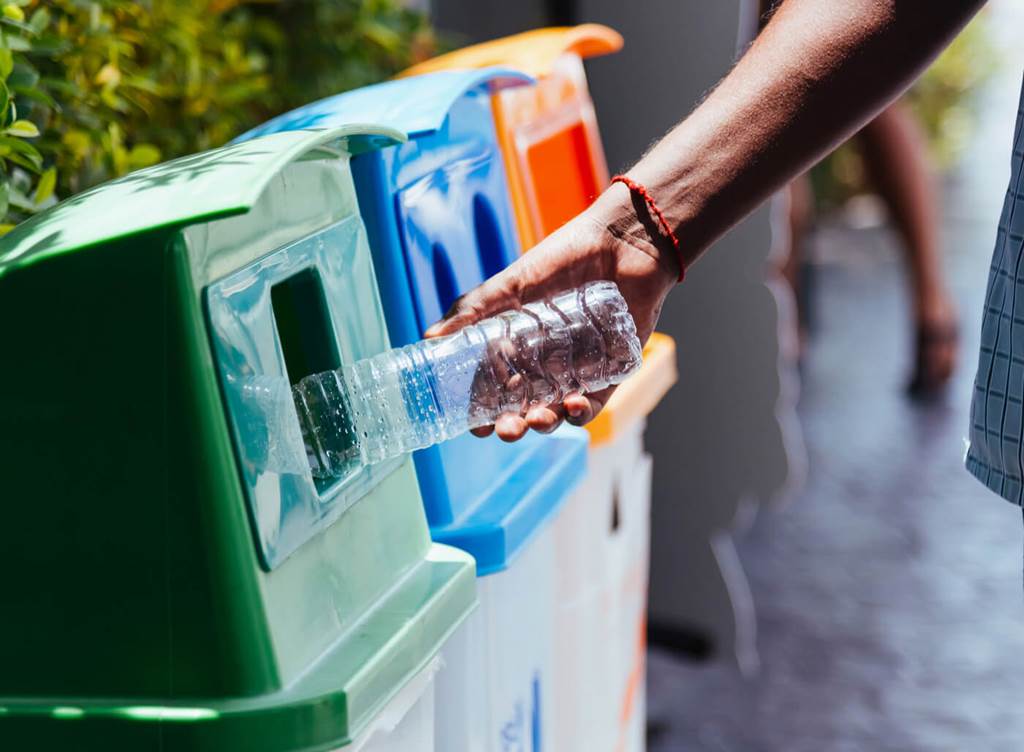 person throwing out a plastic bottle in recycling