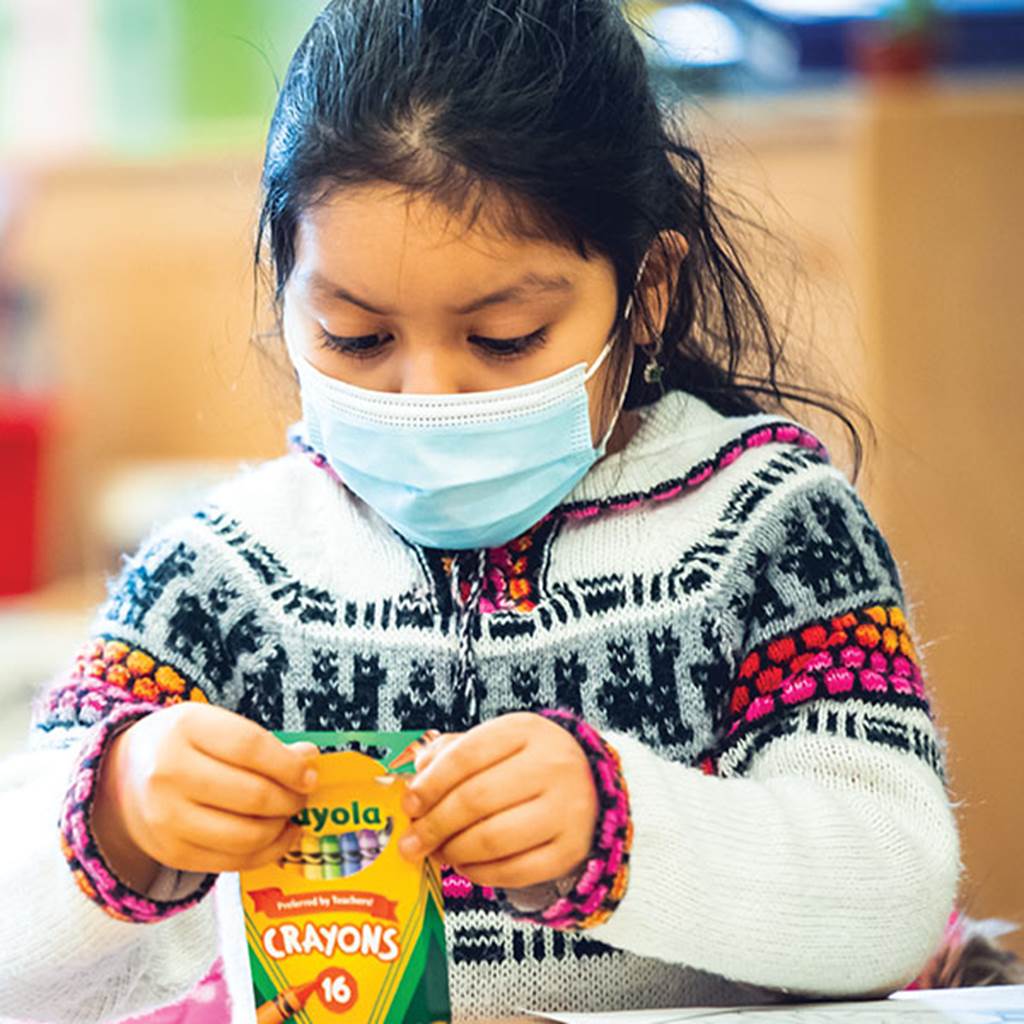 Image of a young student opening a box of crayons