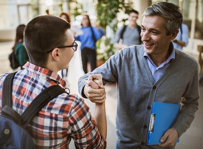 Teacher and high school student shaking hands