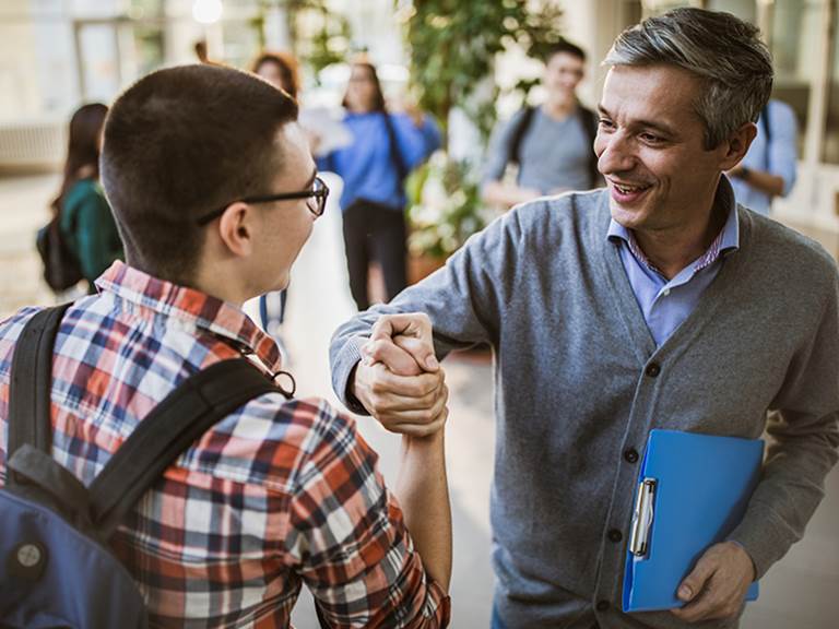 Teacher and high school student shaking hands