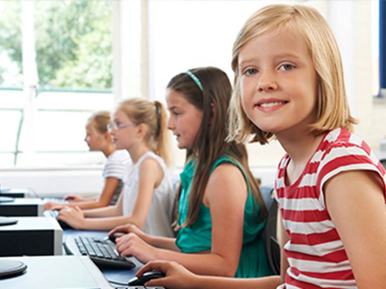 Four 8th grade girls typing on computer keyboards