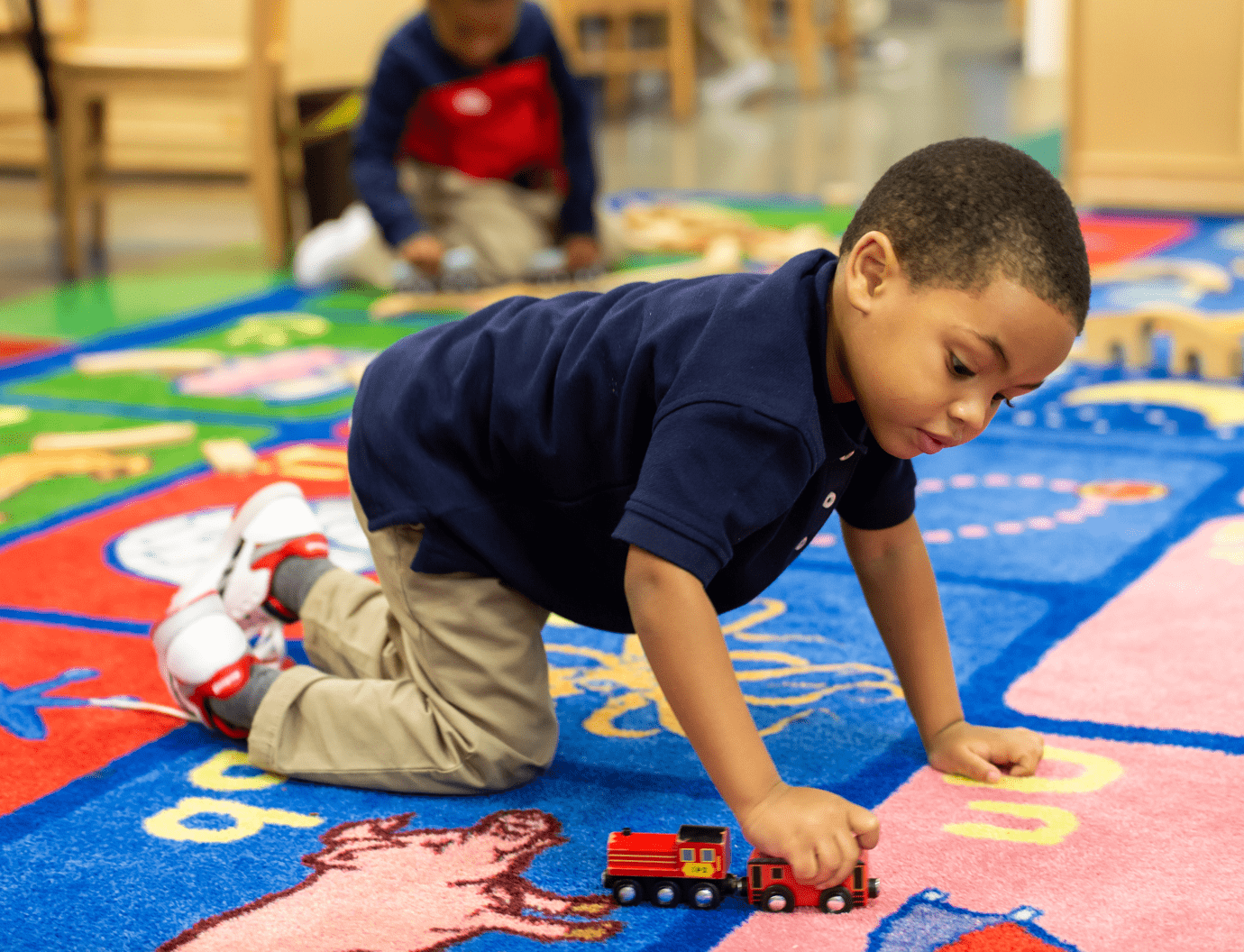 Boy playing with train on classroom carpet