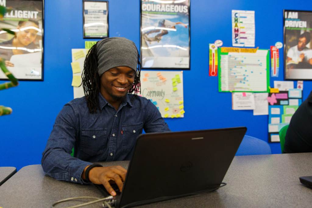 A boy sits in front of a laptop