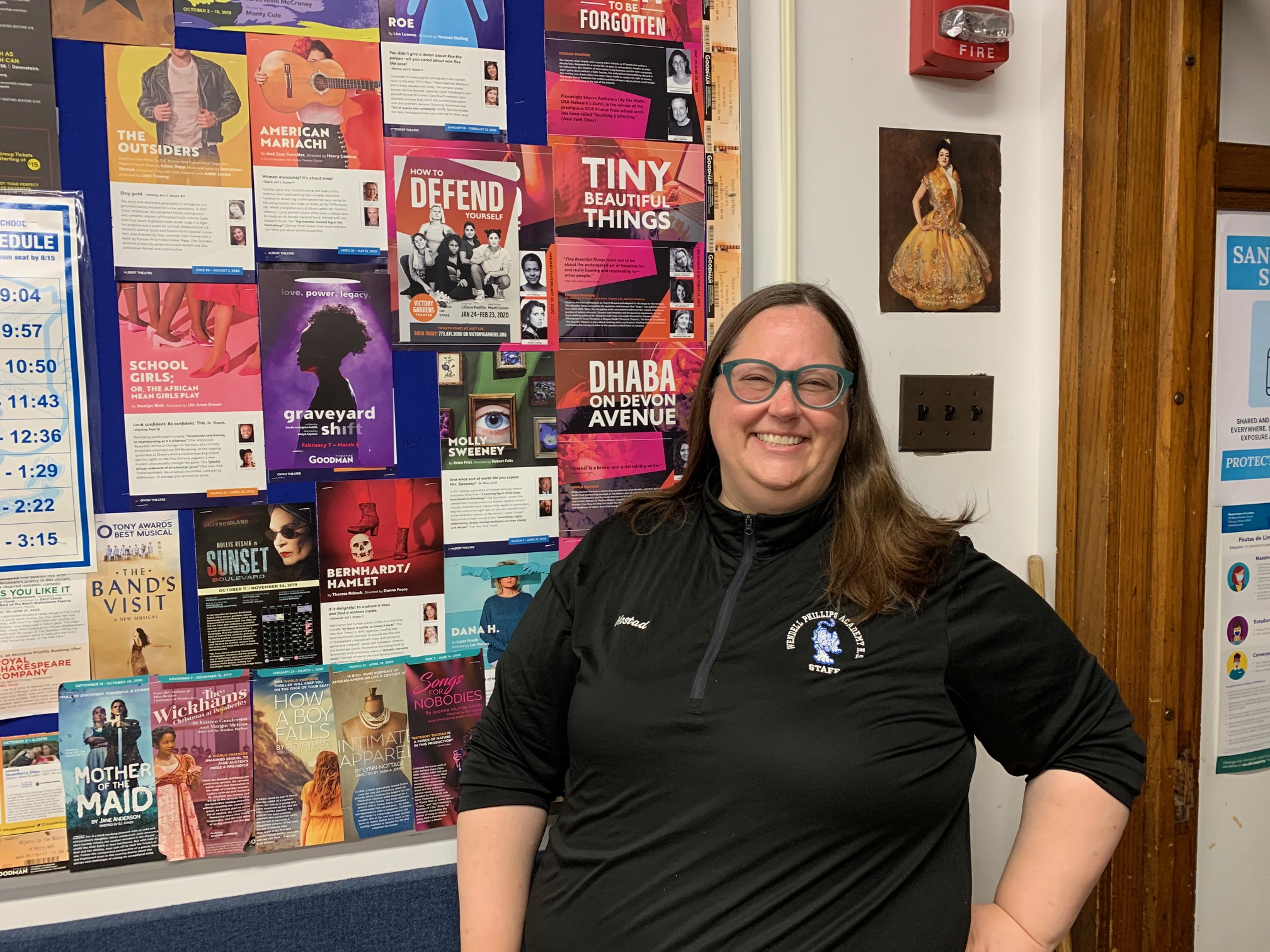 Ms. Sarah Mostad standing in front of a collage of posters