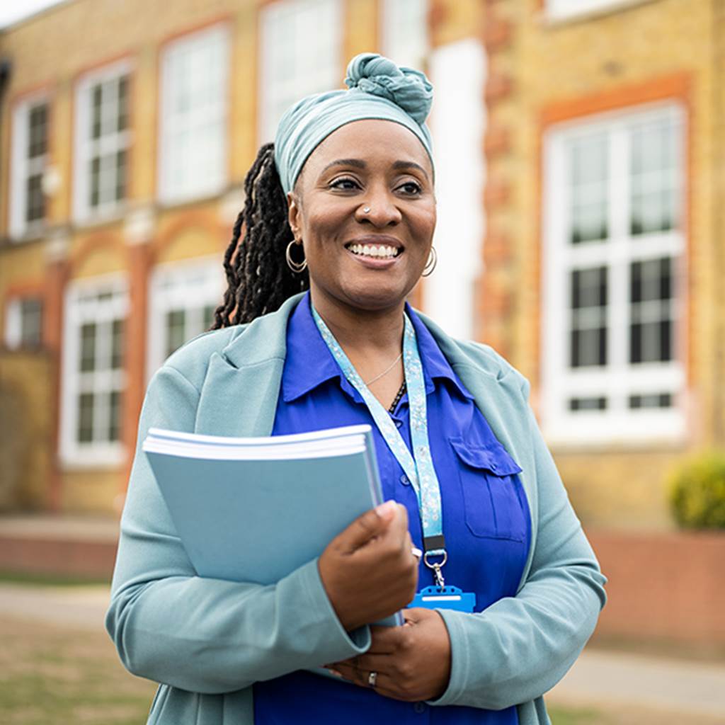 A parent carries papers on a school campus